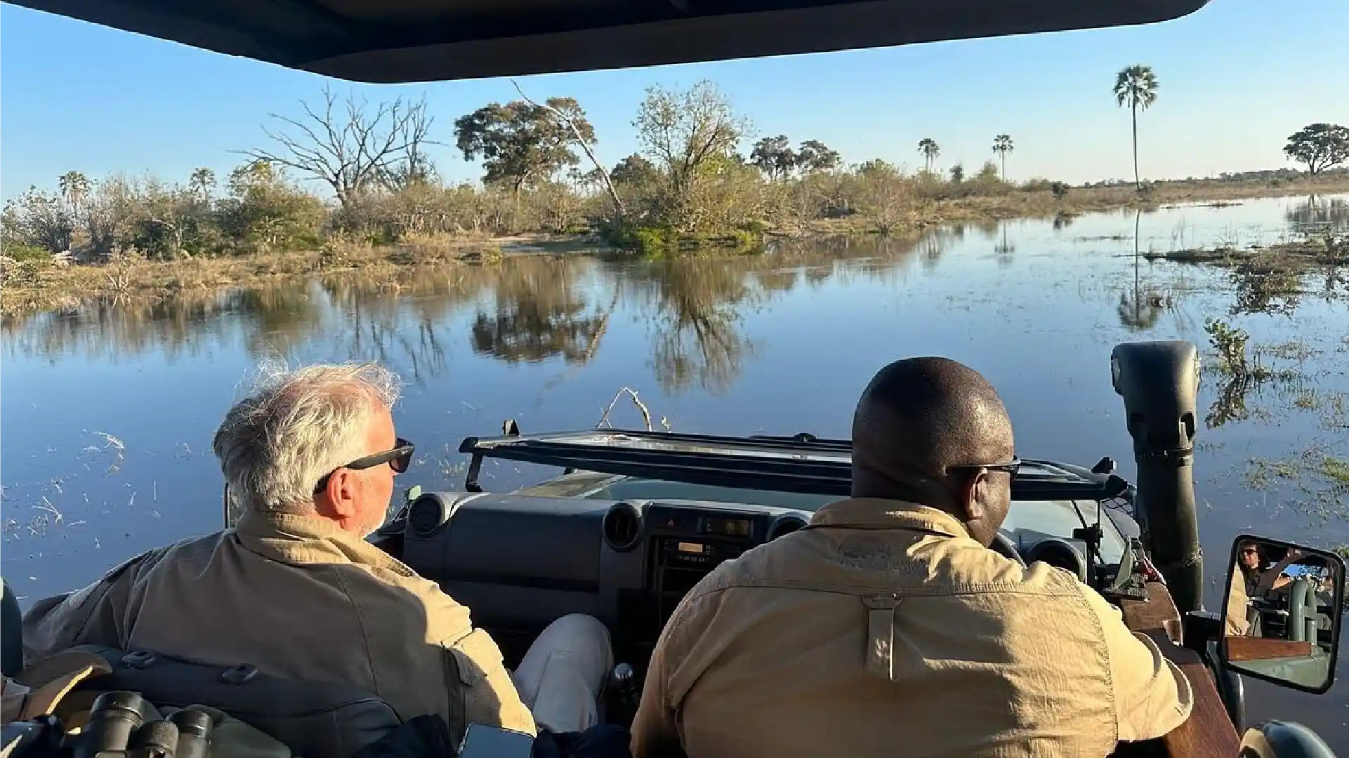 Safari guide and guest exploring Botswana's waterways in an open safari vehicle during a guided game drive.