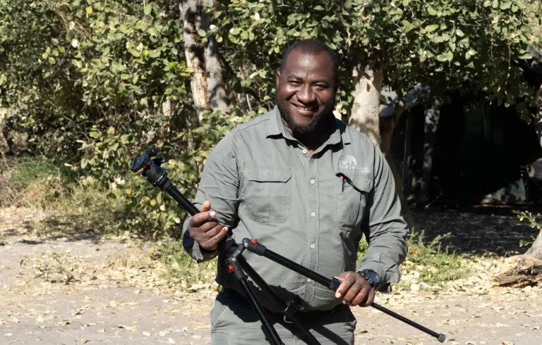 Wild for Game Safaris team member holding a camera tripod at a mobile safari camp in Botswana.